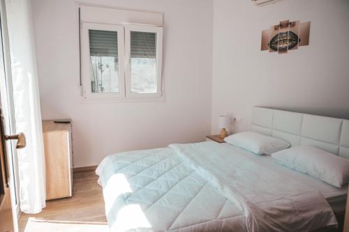 a white bedroom with a large bed and a window at Comfortable apartment in the city center in Katerini