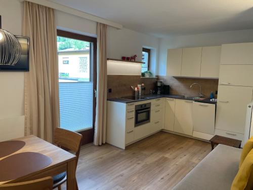 a kitchen with white cabinets and a table and a dining room at Appartements Falkner Dorli in Oetz