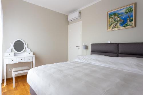 a white bedroom with a white bed and a mirror at GAJO DELUXE in Trogir
