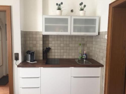 una cocina con armarios blancos y fregadero en Zentral gelegene Remscheider Ferienwohnung, en Remscheid