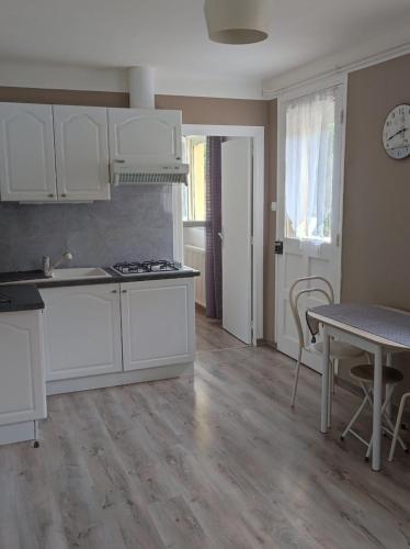 une cuisine avec des armoires blanches et une table et une salle à manger dans l'établissement chambre triple, à Ploubazlanec