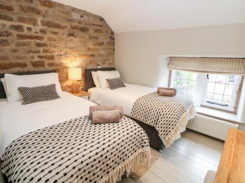 dwa łóżka w pokoju z ceglaną ścianą w obiekcie Robin's Nest w mieście Bakewell