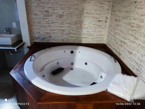a white bath tub in a bathroom with a sink at Chalé Villa Magrini in Monte Verde