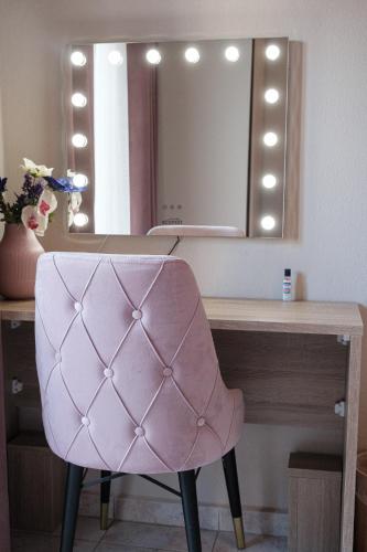 einen rosa Stuhl vor einem Schreibtisch mit einem Spiegel in der Unterkunft Remvi in Komotiní