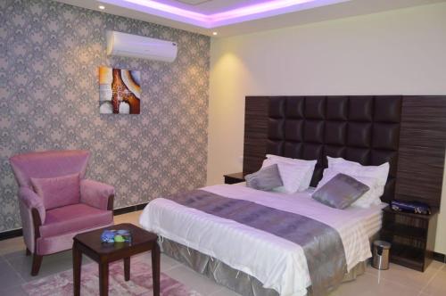 - une chambre avec un grand lit et une chaise dans l'établissement فندق رذاذ, à Al Kharj