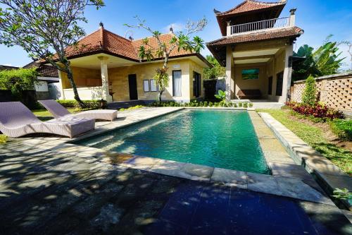 a swimming pool in front of a house at Adil Villa & Resort in Ubud