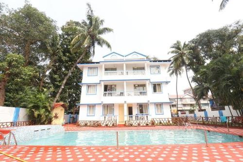 a large white house with a swimming pool in front of it at Blue Lagoon Benaulim Goa in Marmagao