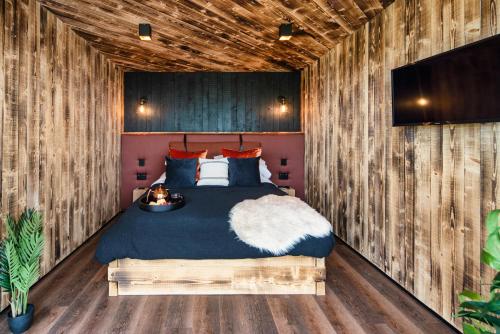 a bedroom with a bed in a wooden wall at Rusty Boathouse in Llanarth