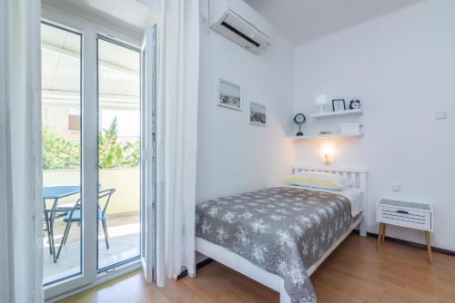 a bedroom with a bed and a table and a balcony at Apartment Luiza with Terrace in Baška