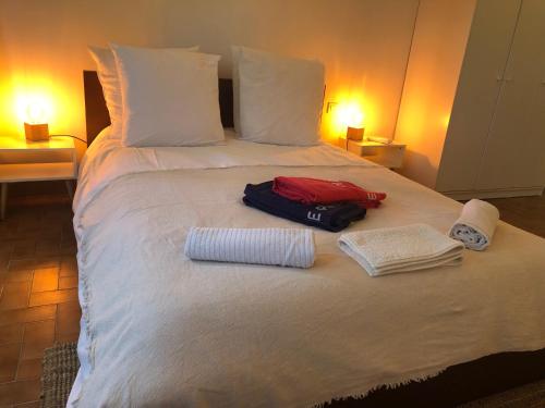 ein weißes Bett mit zwei Handtüchern und einem Koffer darauf in der Unterkunft La Tour- Pigeonnier Provençal - Mas des Sous Bois in Ventabren