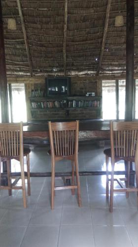a table with three chairs and a piano in a room at Meru Mbega Lodge in Usa River