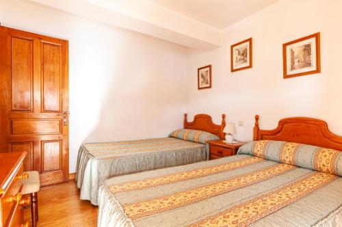2 Betten in einem Zimmer mit weißen Wänden und Holzböden in der Unterkunft Casa Enrique en el oriente de Asturias in Quintana de Llanes