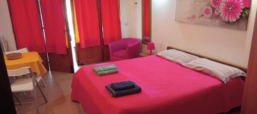 una camera con letto rosso, tavolo e sedia di Appartamento Seflonia a Cefalù