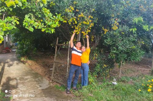 two people are standing under a fruit tree at Bebe Homestay Phu Quoc in Phu Quoc