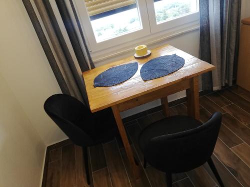 una mesa de madera con 2 sillas y una ventana en Studio apartman Noa en Rijeka