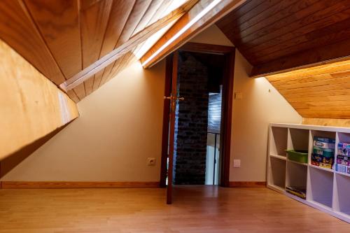 an attic room with a wooden ceiling and an open door at Le verger de La Haze in Esneux