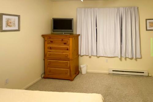 a bedroom with a dresser with a television on top of it at Brigantine Condo with Gas Grill - Walk to Beach! in Brigantine