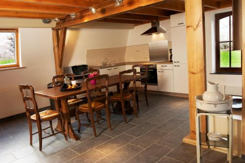Au détour du Trieu في Estaimbourg: مطبخ مع طاولة وكراسي خشبية في الغرفة