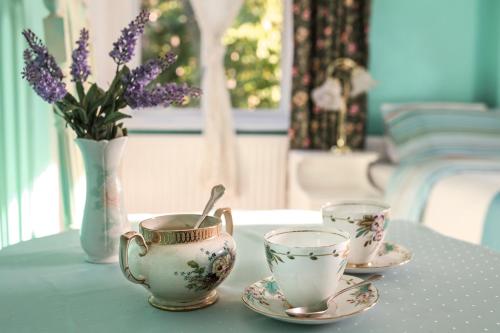 una mesa con dos tazas de té y un jarrón con flores púrpuras en Dawson Place, Juliette's Bed and Breakfast, en Londres