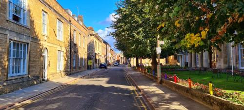 an empty street with buildings and a car on the road at Luxurious two-bedroom apartment in the centre of Peterborough in Peterborough