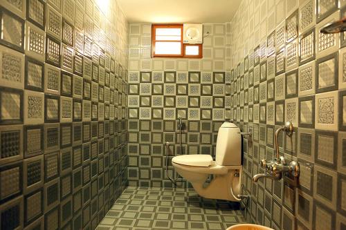 a bathroom with a toilet and a tiled wall at Aleenas homestay in Cochin