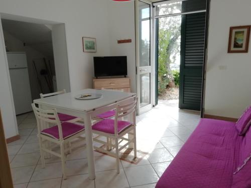 comedor con mesa blanca y sillas moradas en Casa vacanza Marina di Andrano zona Grotta Verde, en Andrano