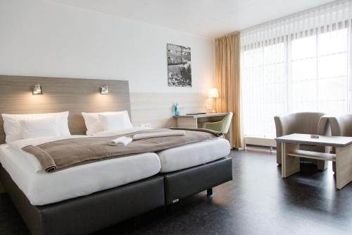a hotel room with a large bed and a desk at Friesen Hotel in Jever