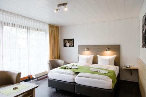 a bedroom with a large bed with a green blanket at Friesen Hotel in Jever