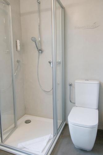 a bathroom with a shower and a toilet at Friesen Hotel in Jever