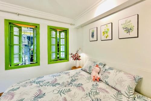 a bedroom with a bed and green windows at Vitamin Home Hoàn Kiếm 35 in Hanoi