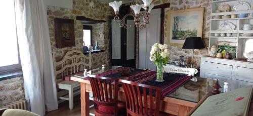 Un comedor con una mesa con un jarrón de flores encima. en La Casina de Valles de San Román, en La Busta