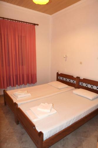 two beds in a room with a red curtain at Splantza Apartments in Ammoudia