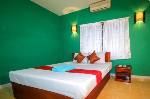 a bedroom with green walls and a bed with white sheets at Blossoming Romduol Boutique in Siem Reap