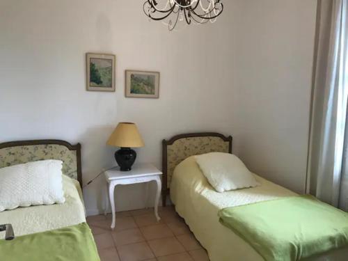 a bedroom with two beds and a table with a lamp at La Bastide Plein Sud de Marignan in Saint-Gilles