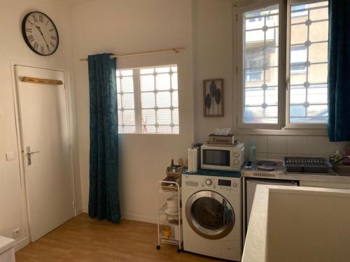 eine Küche mit einer Waschmaschine und einer Uhr an der Wand in der Unterkunft Duplex Cosy proche Paris(5mn)sans commission en + in Alfortville