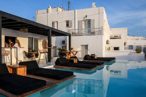 a pool with chairs and a house in the background at Casa Anna Suites in Mikonos