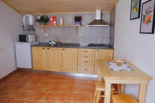 une cuisine avec une table en bois, une table et un comptoir dans l'établissement Casinha da Eira, à Góis