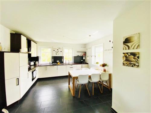 a kitchen with a table and some white cabinets at Exklusives Ferienhaus "An der Nordsee" in Großheide