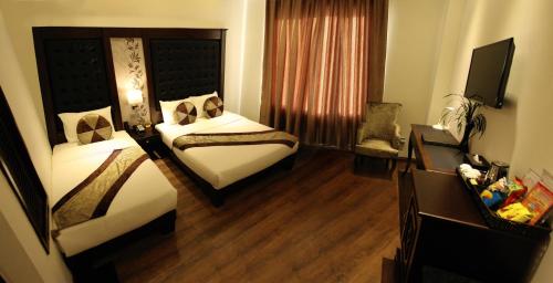 a hotel room with two beds and a television at CityBay Palace Hạ Long Hotel in Ha Long