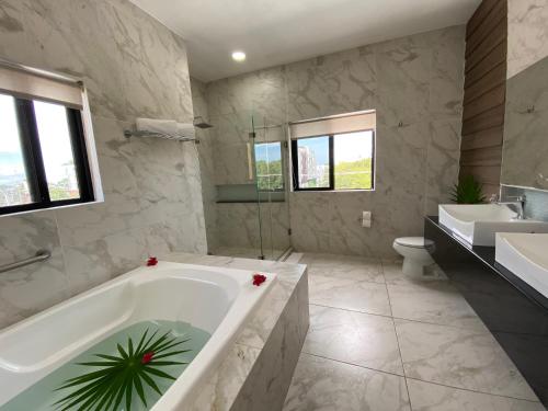 y baño con bañera, aseo y lavamanos. en Hotel Las Golondrinas en Playa del Carmen