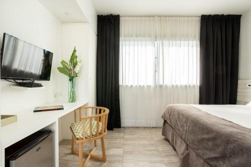a hotel room with a bed and a tv and a chair at Hotel BA Jardines Palermo in Buenos Aires