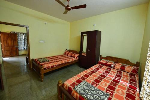 a bedroom with two beds and a ceiling fan at GAHANASHREECOTTAGE in Subrahmanya