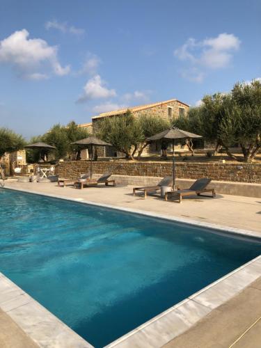a swimming pool with benches and umbrellas next to a building at Afentiko Pigadi in Methoni