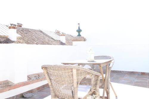 una mesa y sillas en un balcón con una pared blanca en Casco Historico Apt. Doña Concha en Ronda