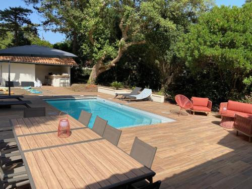 a patio with a table and chairs and a swimming pool at Villa de charme avec piscine à 500m des plages in Soorts-Hossegor