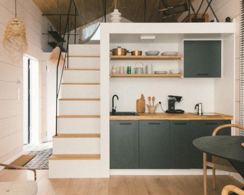 a kitchen with stairs leading up to a kitchen with green cabinets at Fejny Dom - Jezioro Dadaj in Kromerowo