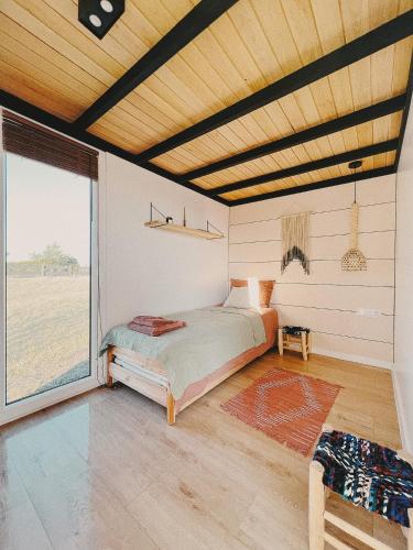 a bedroom with a bed and a large window at Fejny Dom - Jezioro Dadaj in Kromerowo