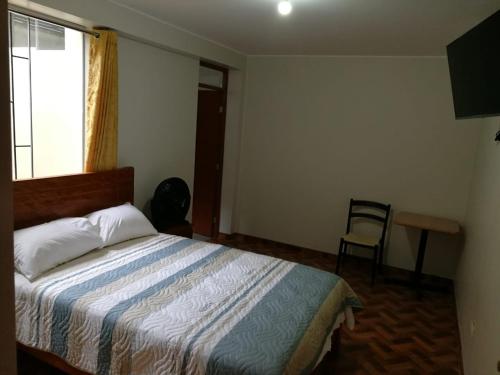 a bedroom with a bed and a window and a chair at El Sol de Nazca in Nazca