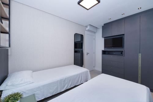 1 Schlafzimmer mit 2 Betten und einem TV in der Unterkunft Adra 206 - Apartamento no centro de Bombinhas - Rooftop com piscina e academia - À poucos metros da praia - (Consultar serviços de roupas de cama e banho) in Bombinhas