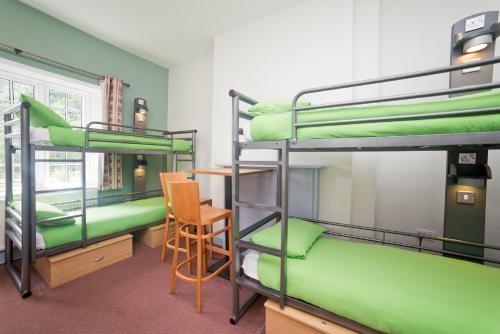 Zimmer mit 2 Etagenbetten und einem Stuhl in der Unterkunft YHA Ilam Hall in Ashbourne